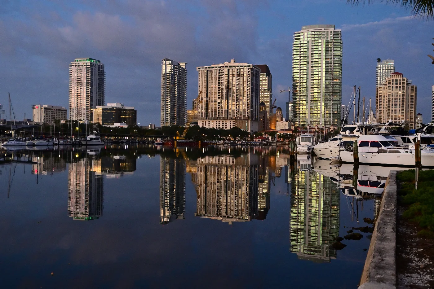Downtown St. Petersburg towers and boats reflected in calm marina water before sunrise
